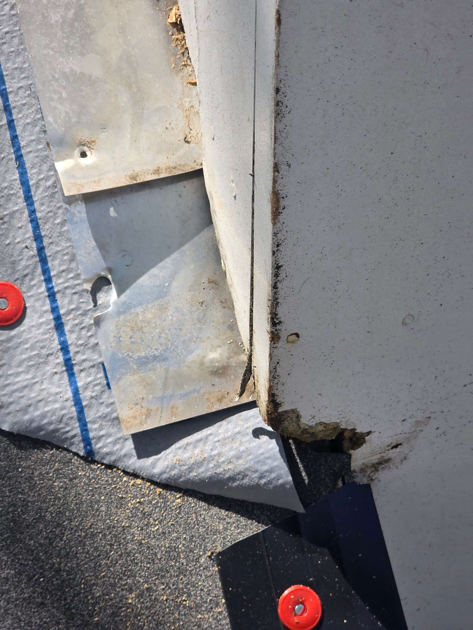 Exposed metal flashing and deteriorated trim at a roof-to-chimney junction